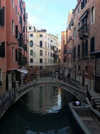 Canal in city against sky