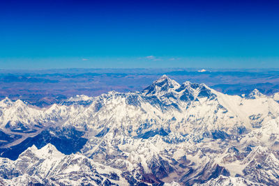 Aerial view of snowcapped mountains against blue sky