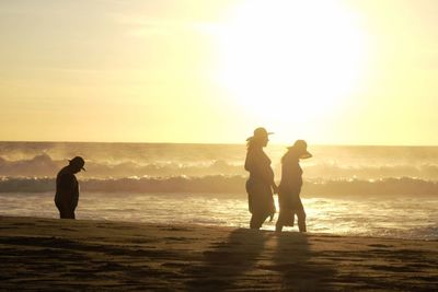 Silhouette of people on beach at sunset