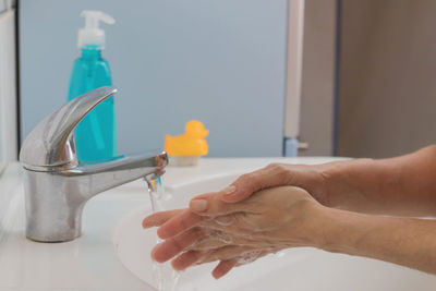 Close-up of hand holding bottle against blurred background