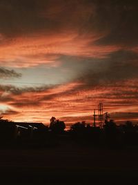 Silhouette trees on field against orange sky