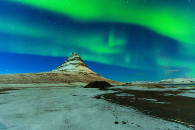 Scenic view of snowcapped mountain against sky at night
