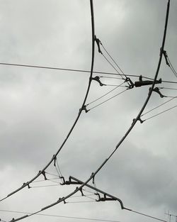 Low angle view of power lines against cloudy sky