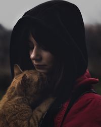 Close-up of young woman holding cat during sunset