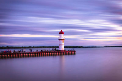 Lighthouse by sea against sky