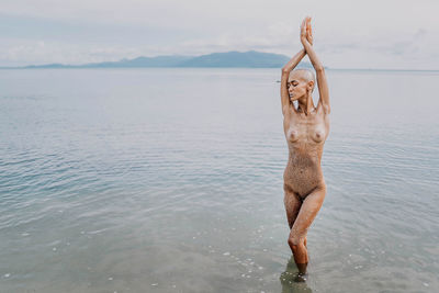 Bald girl in sequins swims in the sea