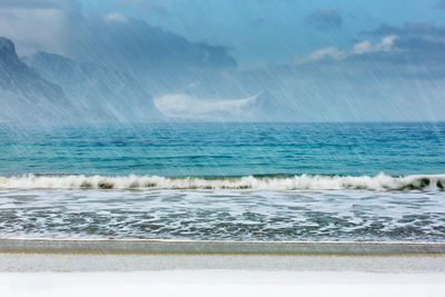 Long exposure of snow fall on beach against sea