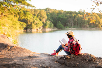 Man sitting by lake against trees