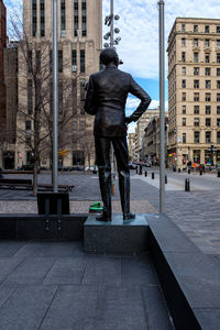 Man statue on street against buildings in city