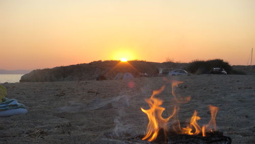Close-up of fire on field against clear sky during sunset