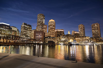 River by illuminated buildings against sky at night