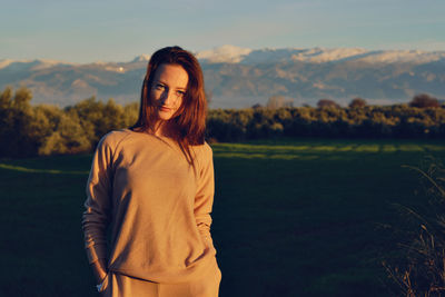 Woman standing on field against sky during sunset