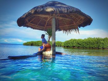Side view of man sitting under parasol in lake