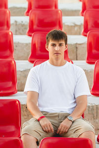 Bored young man sitting in deserted audience with seats. absence of people in open-air amphitheater