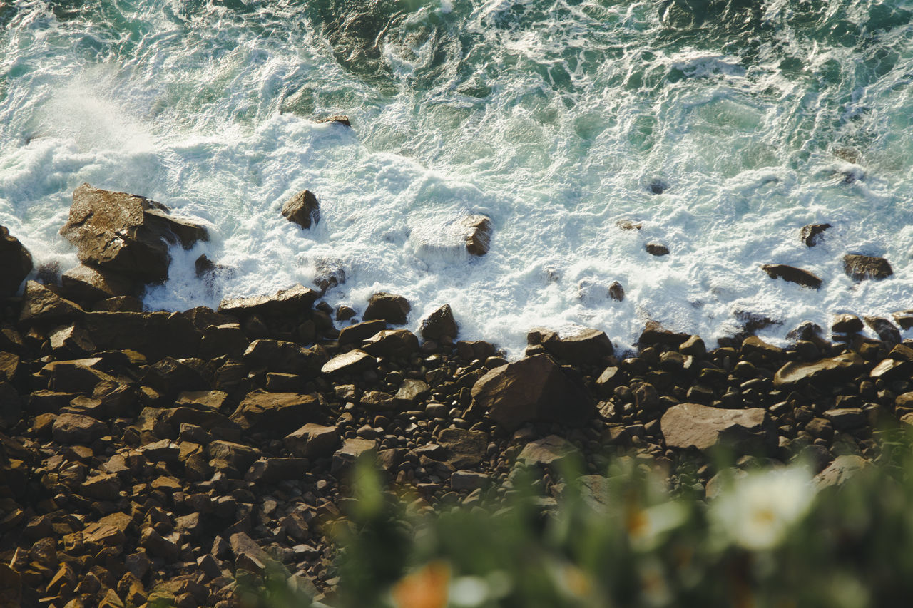 HIGH ANGLE VIEW OF ROCKS ON SEA