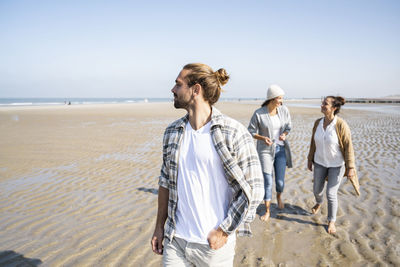 Women standing on beach against clear sky