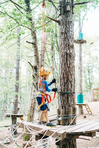 Woman by tree trunk in forest