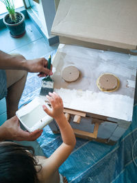 High angle view of man and child hand holding brush to paint