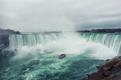 High angle view of waterfall in forest against cloudy sky