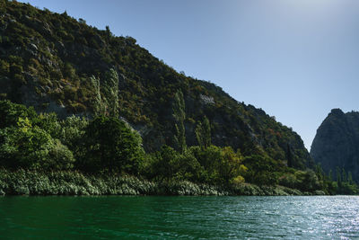 Scenic view of sea and mountains against clear sky