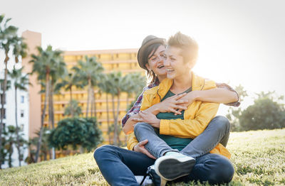 Lesbian couple embracing while sitting on field