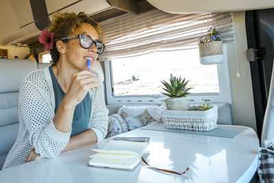 Young woman using phone while sitting on table at home