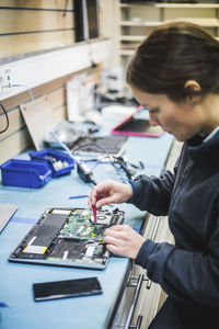 Mature female engineer repairing equipment in computer store