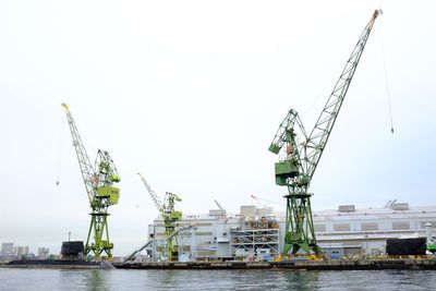 Cranes at commercial dock against clear sky