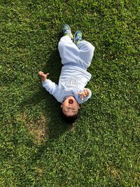 High angle view of boy lying on grassy field