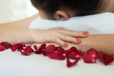 Close-up of woman lying by flower petals on massage table