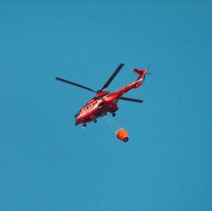 Low angle view of airplane flying against clear blue sky