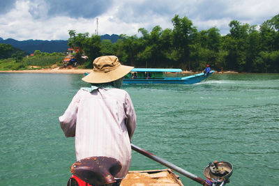 Rear view of man on boat against sky