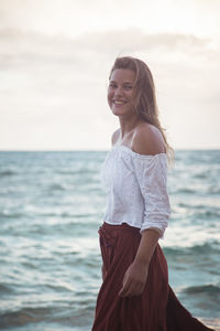 Portrait of smiling young woman standing at beach