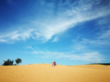 Couple walking on sand against sky