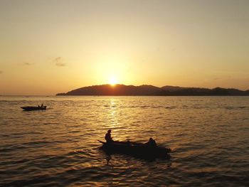 Silhouette boat in sea against sky during sunset