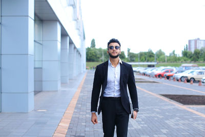 Young businessman standing against building