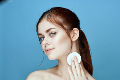 Portrait of smiling young woman against blue background