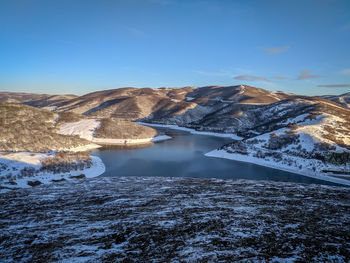 Aerial view of snowcapped mountains against blue sky