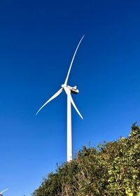 Low angle view of wind turbine against clear blue sky