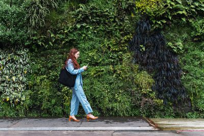 Beautiful young business woman looking at her smart phone while walking. empty space for text