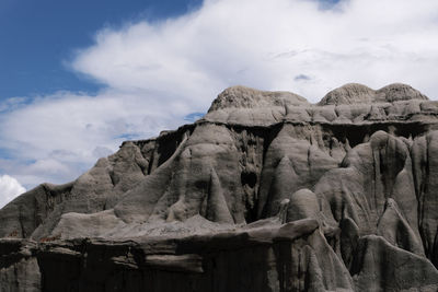 Low angle view of rock formations against cloudy sky