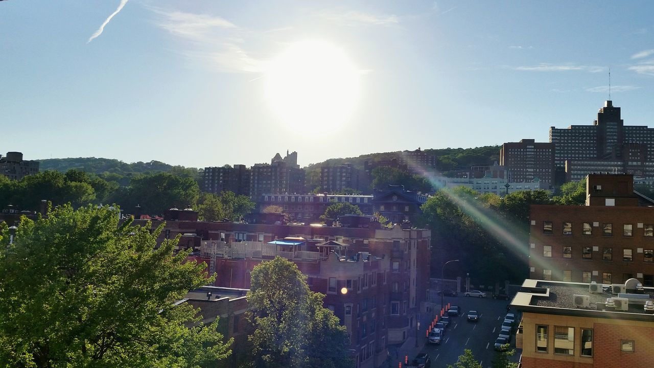 building exterior, architecture, built structure, sun, city, sunlight, sunbeam, lens flare, car, tree, sky, street, residential building, transportation, high angle view, residential structure, city life, sunny, road, land vehicle