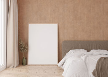 Empty vertical picture frame standing on parquet floor in modern bedroom. mock up interior