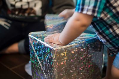 Midsection of boy wrapping gift box at home