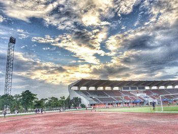 Power lines on landscape against cloudy sky