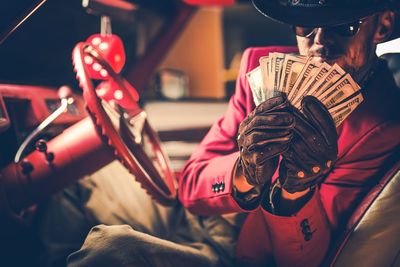 Man holding paper currency in car at night