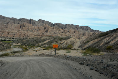 Road by mountains against sky