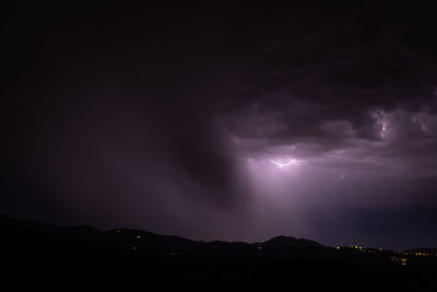 Silhouette of mountain against cloudy sky at night