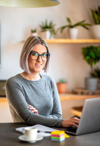 Young woman using phone while sitting on table