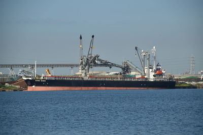 Cranes at commercial dock against sky